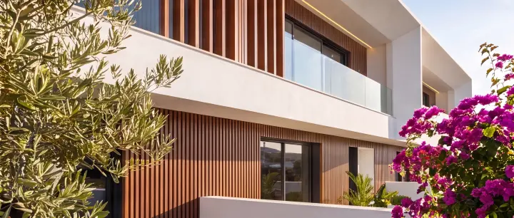 Fachada contemporânea enquadrada por oliveiras e buganvílias